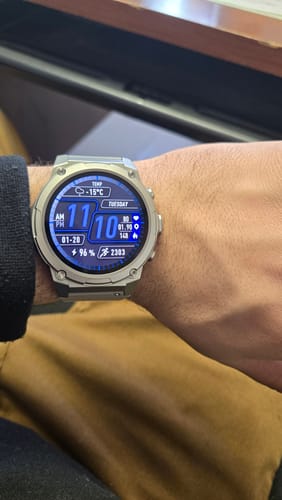 Close-up of a reviewer's silver smartwatch with a blue digital face on their wrist.