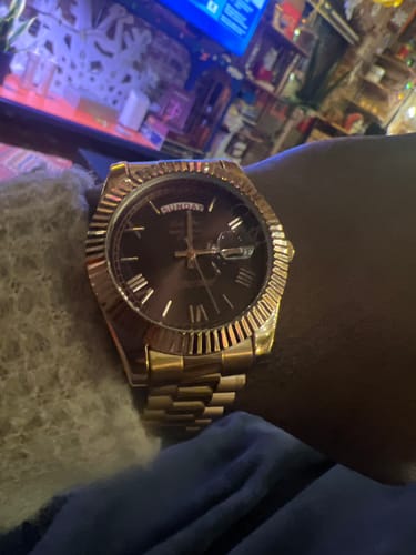 Close-up of a reviewer's gold-toned Lucky Fours® Santos watch with a dark dial, worn on their wrist.