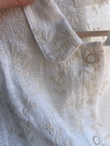 Gros plan de la cliente sur le col Claudine brodé et le tissu en coton de la blouse Amandine.