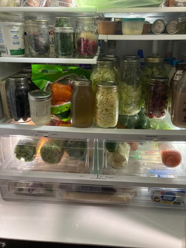 Customer's refrigerator packed with many mason jars of food sealed with the Mason Genie Vacuum Sealer.
