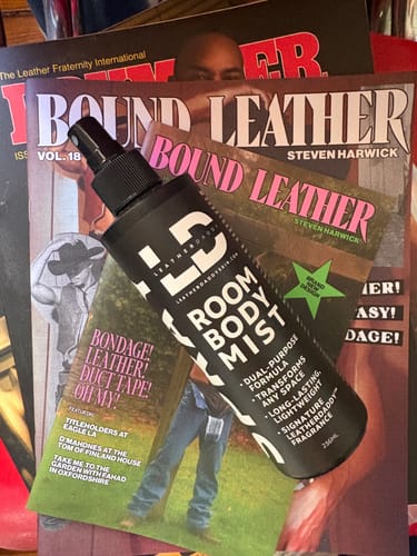 Customer's black bottle of LeatherDaddy Room & Body Mist arranged on a stack of magazines.