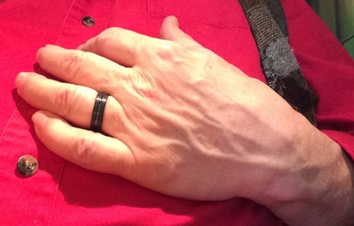 Customer's hand resting on their chest, wearing the black Stratus ring with its blue groove.