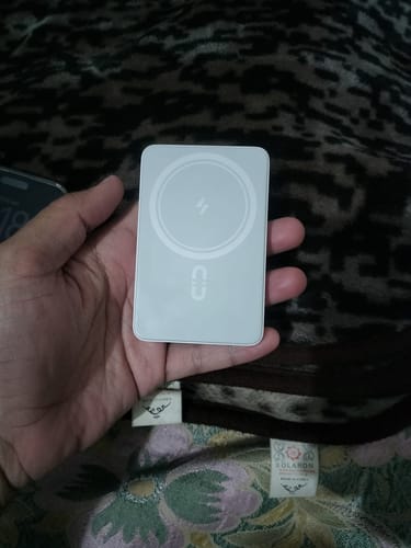 Customer holding the white Romoss Magsafe Wireless Powerbank in their palm, showing its size.