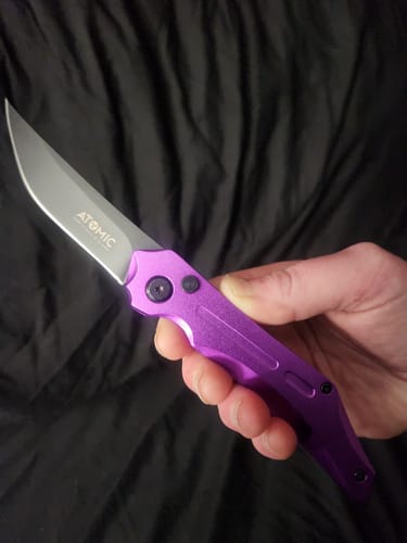Reviewer holding the open Rogue Automatic Switchblade, showing its vibrant purple handle.