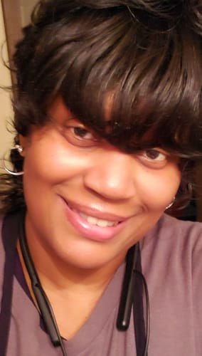 Customer smiling in a close-up, wearing the dark, wavy Chade Fashion Cutie Too Full Wig.