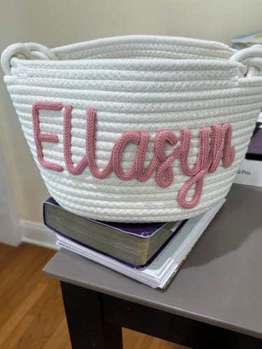 Customer's personalized knitted basket in white with the name 'Ellasyn' in pink.