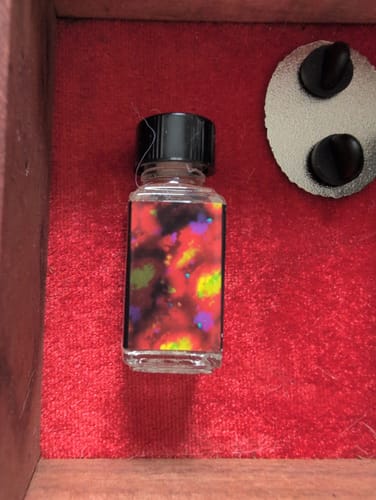 Reviewer's bottle of Opaline Haze with a vibrant, abstract label sitting in a red-lined box.