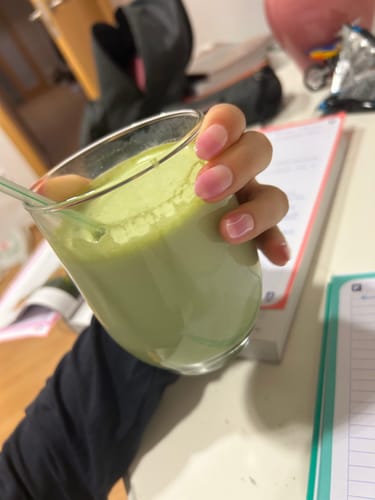 Cliente sosteniendo un vaso de Té Matcha Premium 100% espumoso y verde.
