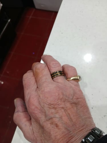Customer's hand wearing the black Rauven ring, showing its hammered texture and gold lines.
