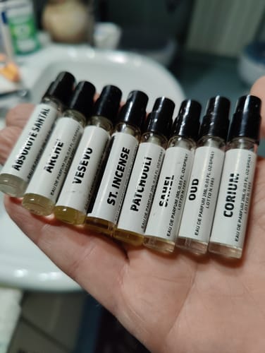 Recensore tiene in mano gli otto campioni di profumo del set orientale e legnoso, disposti a ventaglio.