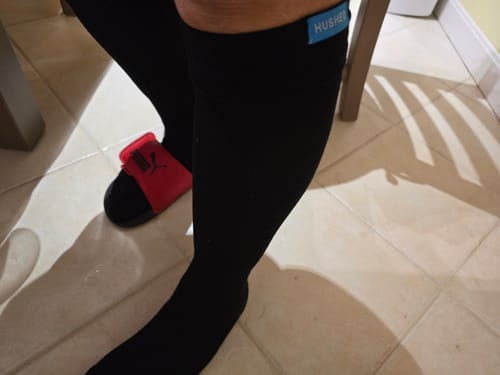 Customer sitting while wearing the black Performance Eucalyptus Compression Socks, showing the knee-high fit.