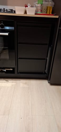 Recensent toont de zwarte by fonQ basic Slide ladekast, geplaatst in een keuken onder het aanrecht.