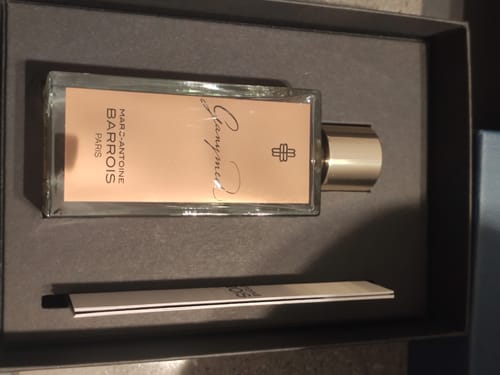 Recensore mostra il flacone di Ganymede eau de parfum sdraiato nella sua elegante confezione aperta.