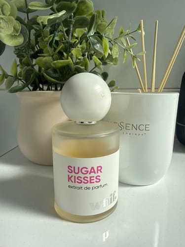 Customer's bottle of Sugar Kisses perfume on a white countertop, placed next to a plant and a reed diffuser.