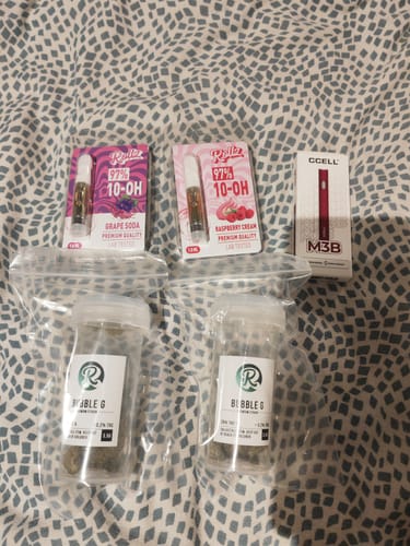 Reviewer's two 10-OH HHC Superior Live Resin Cartridges, 'Grape Soda' and 'Raspberry Cream', displayed with other purchased items.