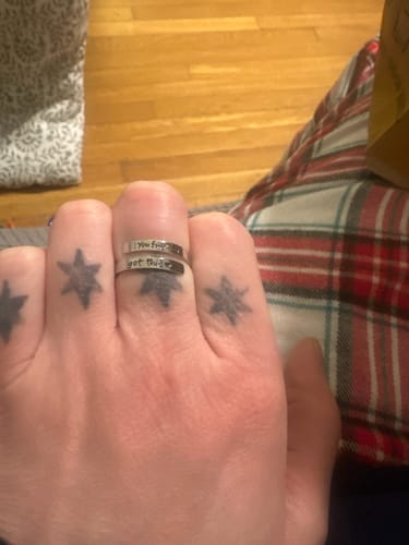 Close-up of the You Fucking Got This Ring on a reviewer's finger, showing the full engraved message.