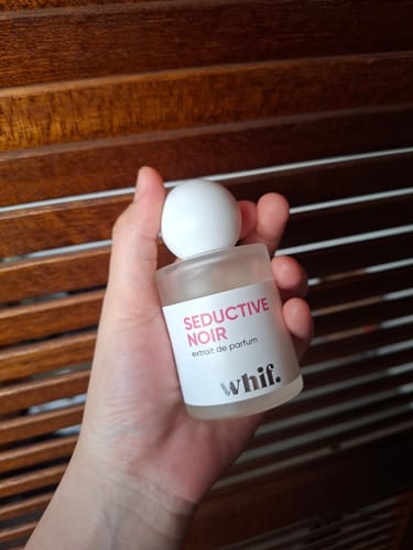 Customer holding the frosted bottle of Seductive Noir perfume in their hand.