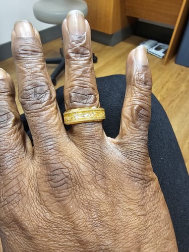 Reviewer's hand displaying the gold Aureum ring with a textured foil inlay.
