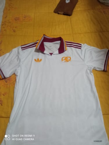 Recensore mostra la Maglia Roma Third bianca stesa su un letto, mettendo in evidenza il colletto rosso.