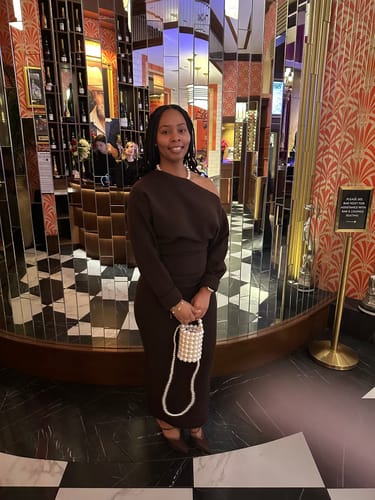 Customer wearing the long, dark Knit Off-Shoulder Sweater Maxi Dress in a stylish lobby.