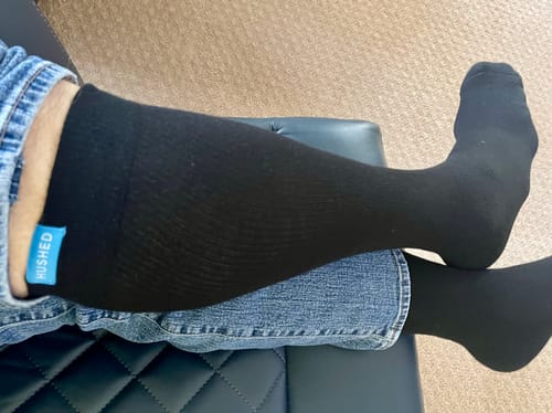 Customer relaxing in their black Performance Eucalyptus Compression Socks with legs crossed.