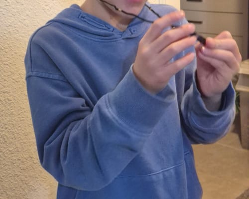 Customer in a blue hoodie holding the Natural Fluorite Necklace in their hands.