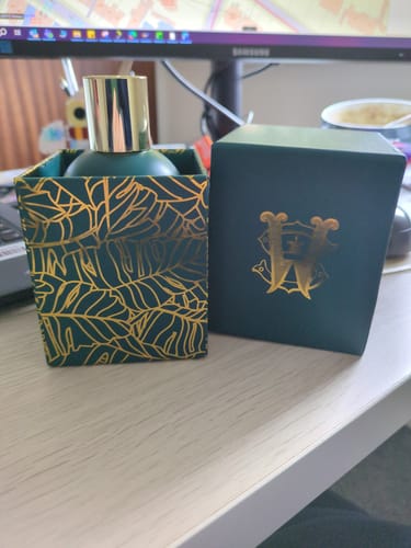 Customer's Ko Meme perfume bottle sitting in its elegant dark green box with a gold leaf pattern.