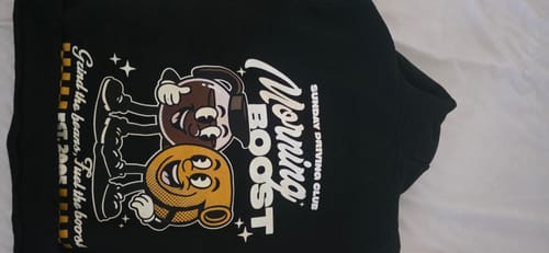 Customer's black Morning Boost Hoodie laid flat, showing the 'Sunday Driving Club' graphic on the front.