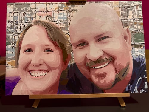 Customer's finished painting from a Custom Paint by Numbers Kit, showing a smiling couple's portrait on a small easel.