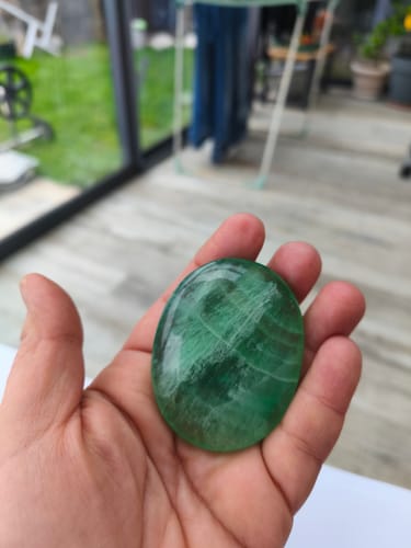 Client tenant un galet de Fluorine vert et poli dans sa main.