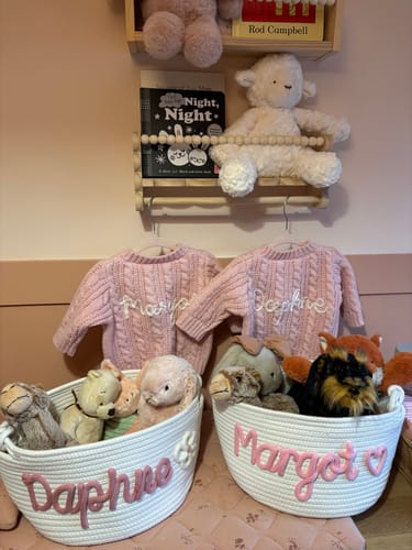 Reviewer's two white baskets personalized with pink names, filled with stuffed animals.