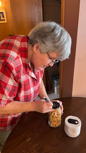 Customer uses a white Liquid Chalk Pen to write on the black chalkboard lid of a glass jar.