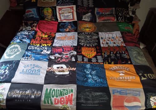 Customer's large Premium T Shirt Quilt spread on a bed, made from dozens of colorful, memorable t-shirts.