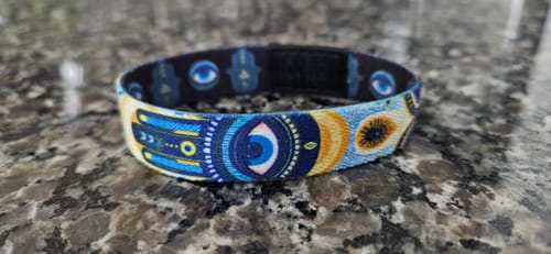 Customer's colorful Allow No Harm Bracelet with hamsa and eye symbols resting on a granite countertop.