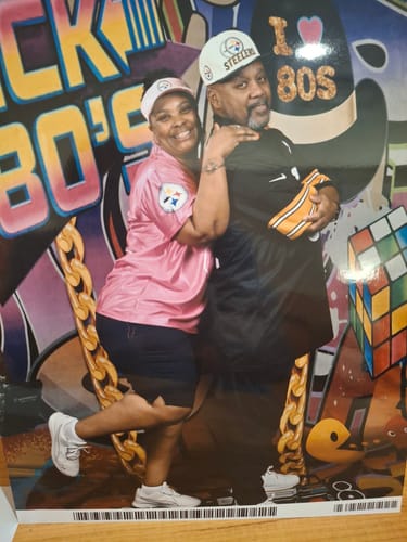 Two reviewers posing happily, one wearing a pink custom cap and the other a white custom cap.
