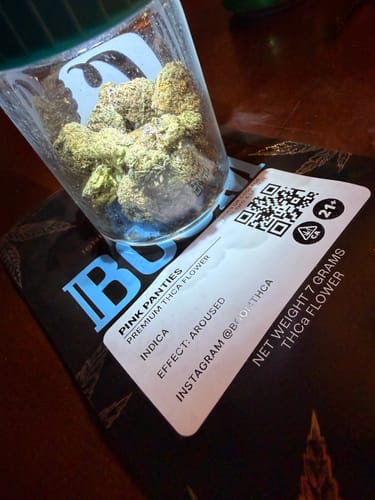Customer's jar of Pink Panties indica flower shown with its black product packaging.