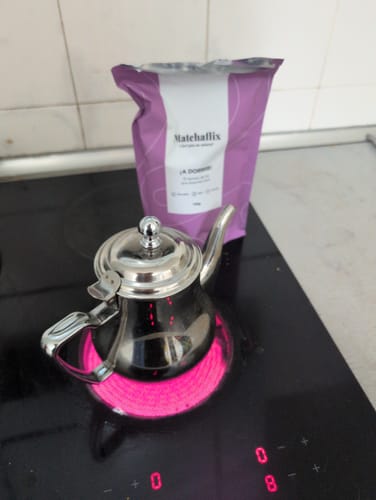 Cliente preparando el producto ¡A dormir! con una tetera metálica en una vitrocerámica encendida.