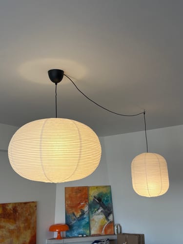 Recensent toont de grote HAY Paper Shade lampenkap die verlicht aan het plafond hangt in een kamer.