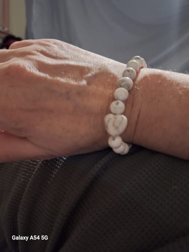 Close-up of a reviewer's wrist wearing a white Howlite bracelet with a heart-shaped bead.