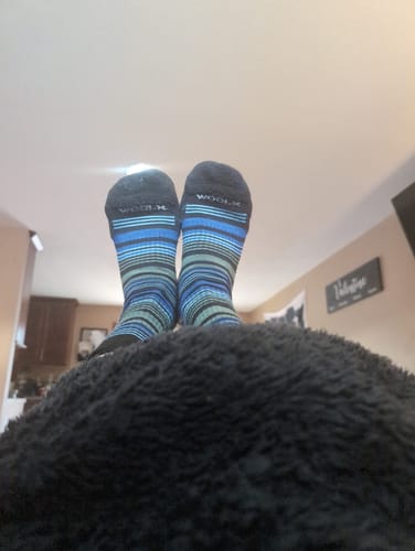 Reviewer relaxing with their feet up, wearing the striped Majolica Blue Everyday Crew Socks.