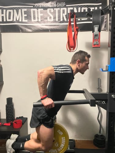 Reviewer performing a weighted dip on the sturdy, black Dip Horns attached to a power rack.