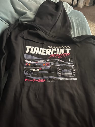 Reviewer's black TOKYO RACING CLUB HOODIE laid out, showing the detailed 'TunerCult' car graphic on the back.