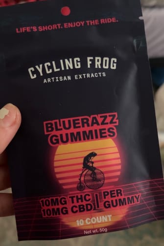 Reviewer holding the black pouch for Blue Razz Gummies, showing the 10mg THC and 10mg CBD dosage.