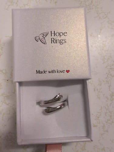 Customer's To My Daughter - Hug Ring, a silver-colored ring with two hands hugging, shown inside its white Hope Rings gift box.