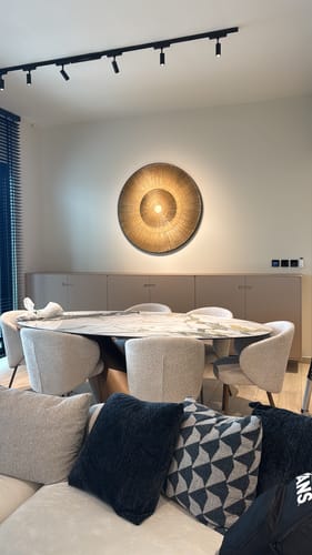 Customer's round, textured paper artwork glowing warmly on a wall above a dining area.