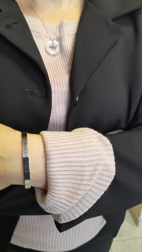Customer wearing the sleek, engraved cuff bracelet on their wrist, styled with a pink sweater and black blazer.