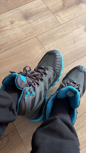 Een klant draagt de grijze en blauwe DF ULTRA ALL TERRAIN BOOTS binnenshuis op een houten vloer.
