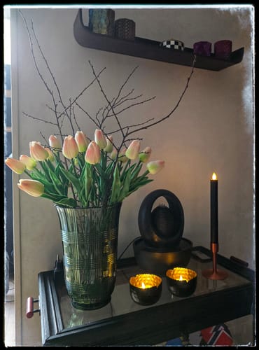 Klant toont het Tulpenboeket Oud Roze in een donkere glazen vaas in een sfeervolle setting.