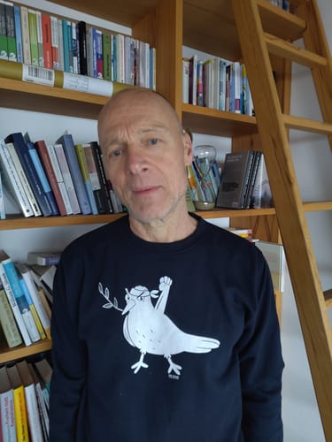 Ein Kunde trägt den schwarzen SWEATER BUBEN mit dem weißen 'POWER PEACE PIGEON'-Aufdruck.