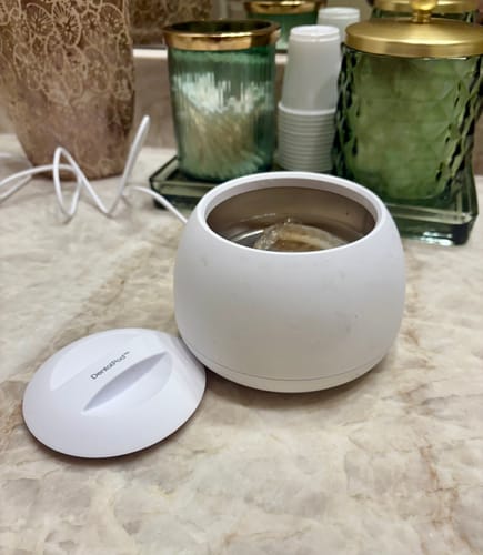 Customer's white DentalPod shown open on a counter with a dental appliance soaking inside.